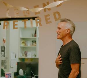 smiling man in t shirt standing with hand on heart