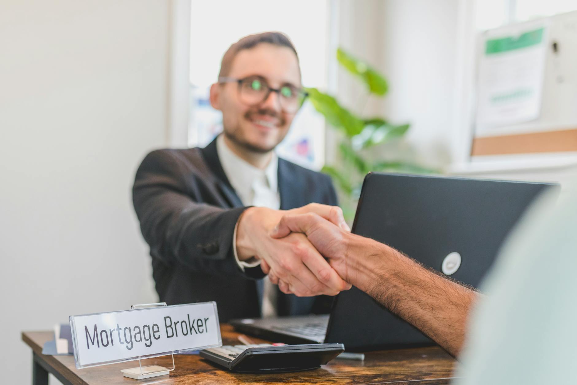 a broker shaking having a deal with the person sitting in front of him
